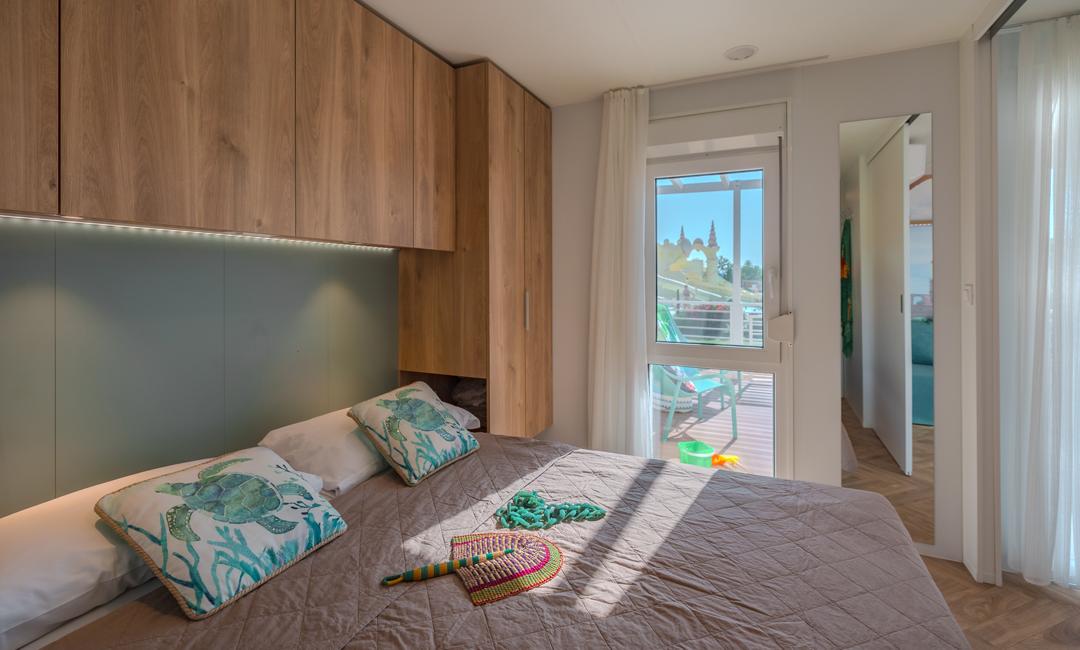 Modern bedroom with wooden cabinets and balcony view.