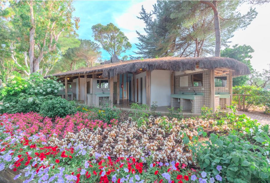 Edificio rustico con fiori colorati e alberi intorno.